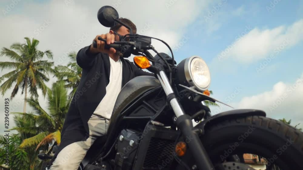 Portrait of caucasian man stopping his motorcylce in tropical