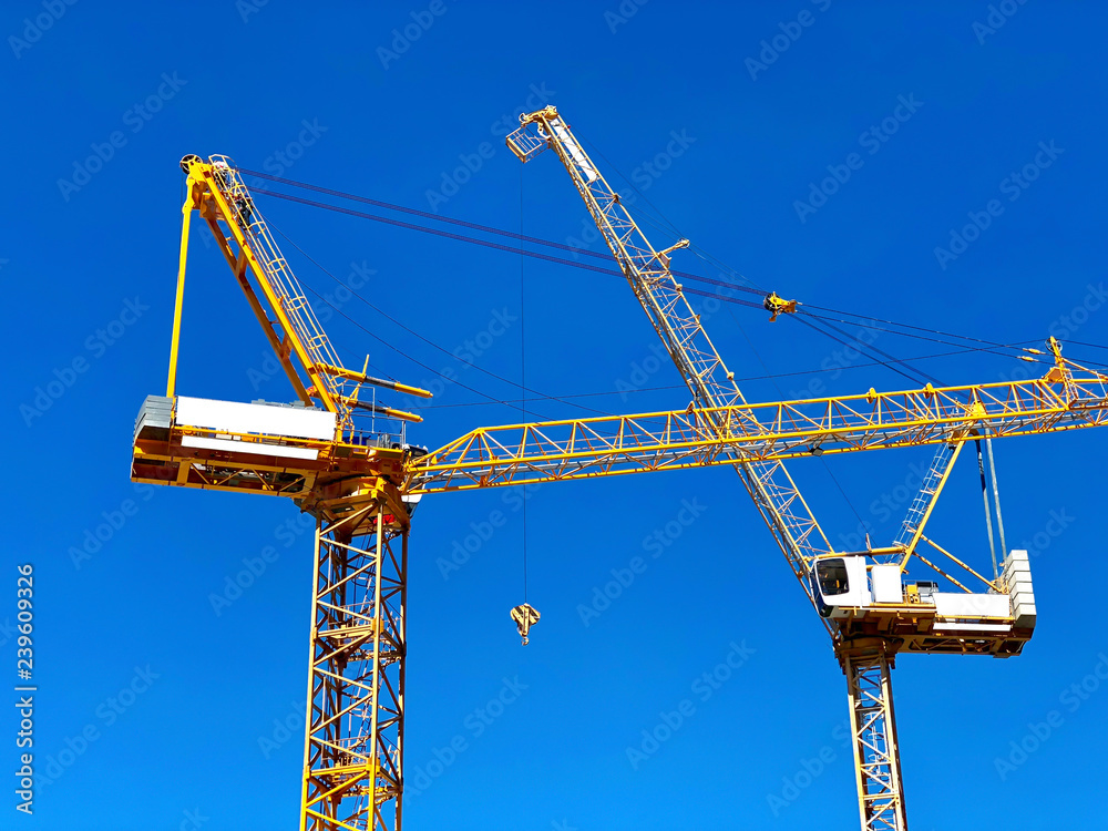 two tower crane construction on blue sky background two tower crane construction on blue sky background