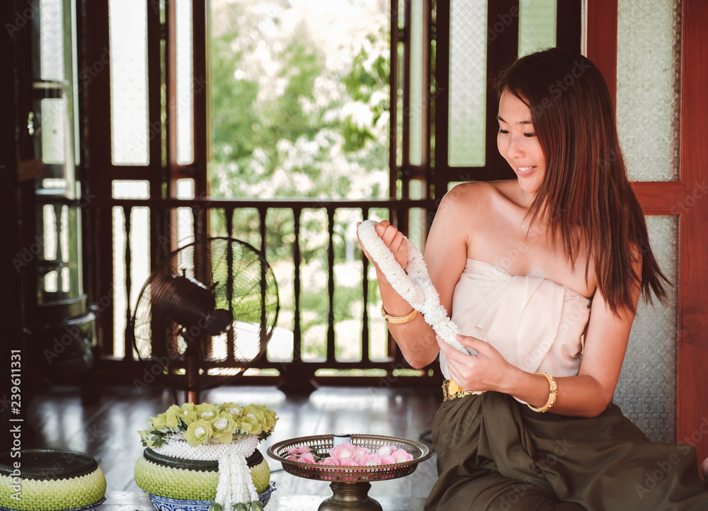 Beautiful Thai girl in traditional costume,making a Thai garland at ...