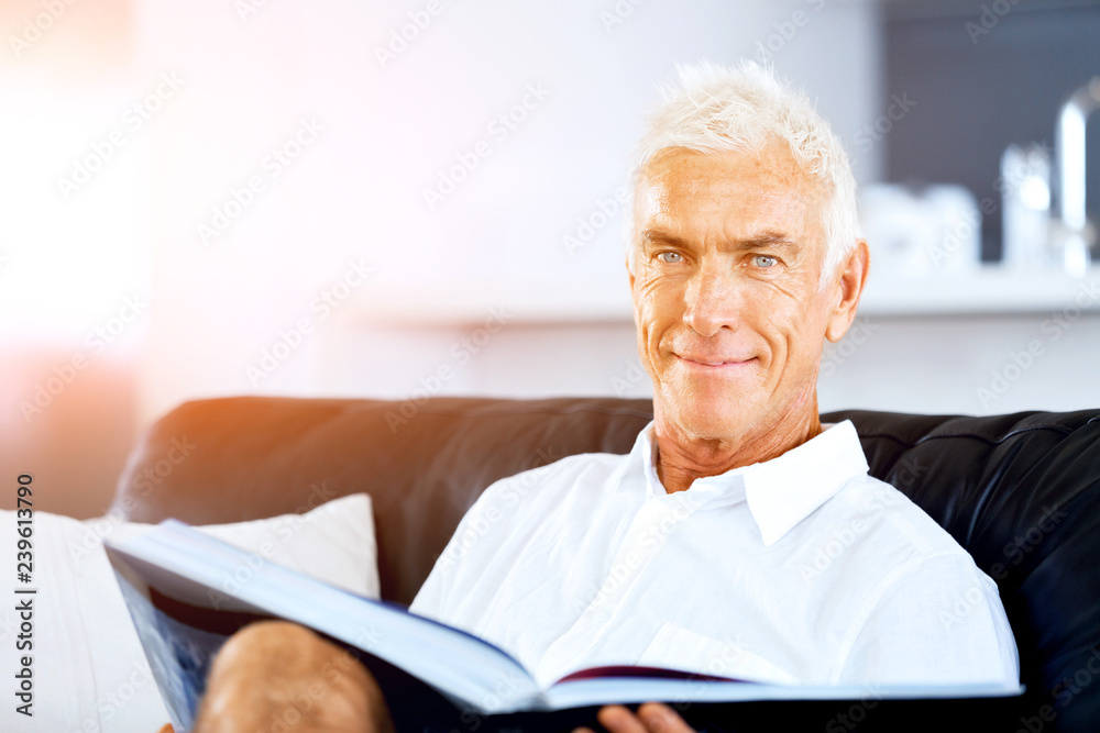 Handsome sennior man reading a book relaxing on a sofa Handsome sennior man reading a book relaxing on a sofa