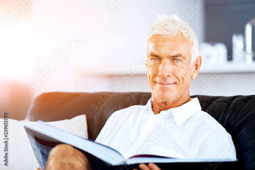 Handsome sennior man reading a book relaxing on a sofa