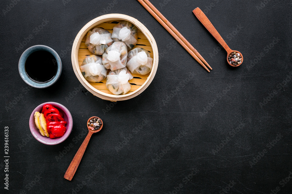 Dinner in Chinese restaurant with dim sum, sticks and tea on black background top view space for text