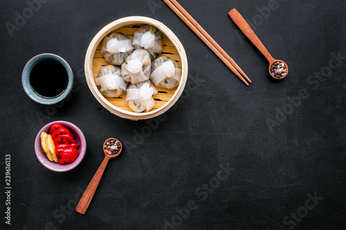 Dinner in Chinese restaurant with dim sum, sticks and tea on black background top view space for text