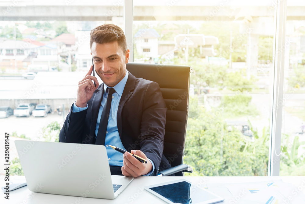Smart businessman using mobile and laptop in office. Smart businessman using mobile and laptop in office.