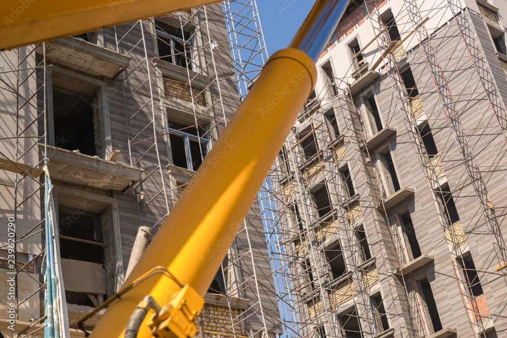close-up of the lifting machine mechanism on the background of the building under construction close-up of the lifting machine mechanism on the background of the building under construction