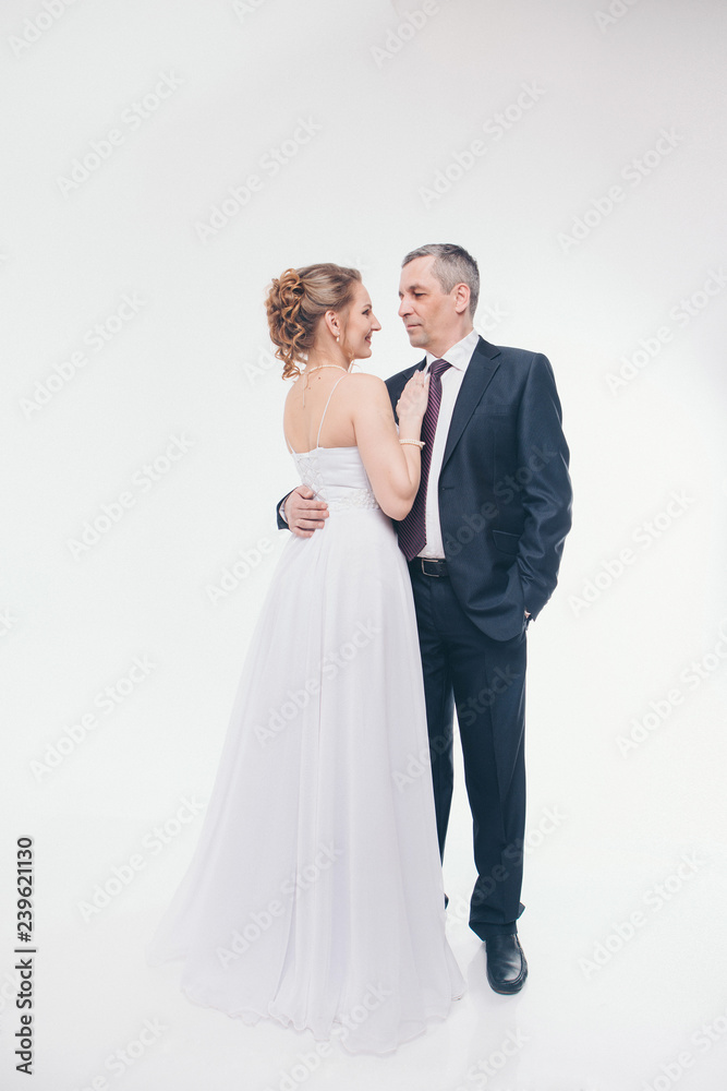 Wedding couple on the nature is hugging each other. Beautiful model girl in white dress. Man in suit. Beauty bride with groom. Female and male portrait. Woman with lace veil. Lady and guy outdoors