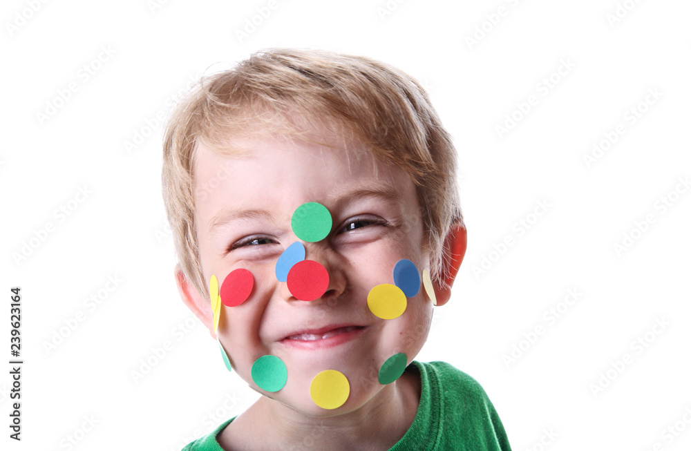 Smiling mischievous boy with round stickers on his face - obrazy, fototapety, plakaty 