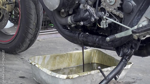 Motorcycle draining old engine oil for maintenance. Handheld slow-motion shot, 29.97fps.