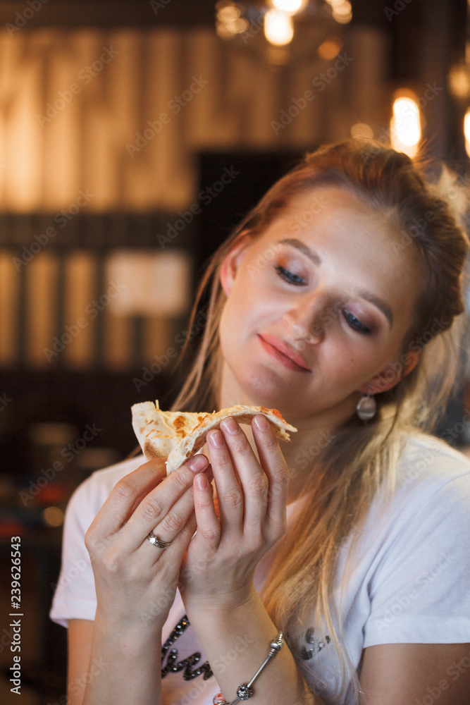 Hipster girl eating pizza in the restaurant and enjoying this Hipster girl eating pizza in the restaurant and enjoying this