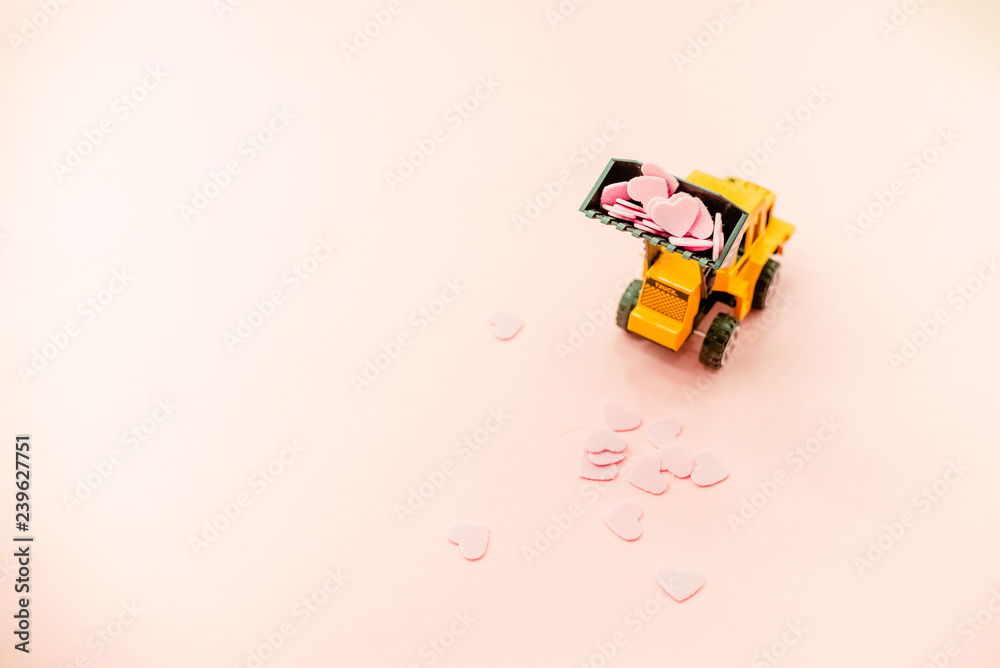 Obraz premium Yellow truck with pink Heart Confetti.Abstract background horizontal top view. Love Day COncept.