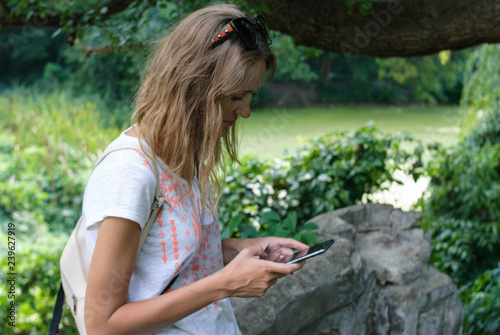 tourist girl looks into the phone in the park