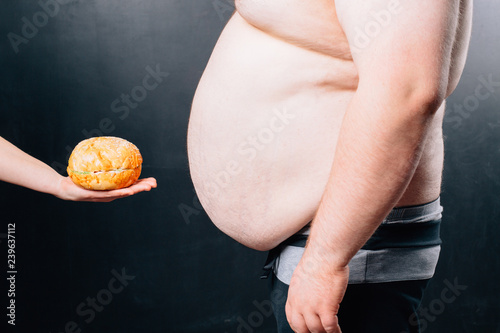 Fat man with a big belly on a dark background. Diet.