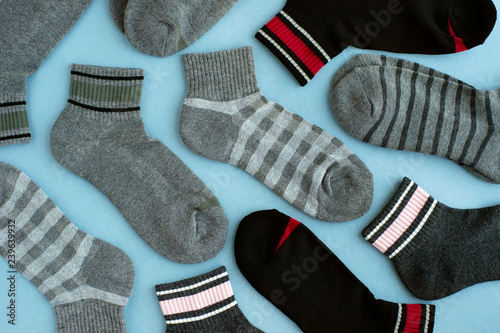 Socks in gray and black tones. Gray and black socks scattered on a blue background. Clothing in the form of socks.