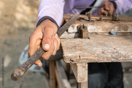 Worker bending steel with steel bending equipment by hand.