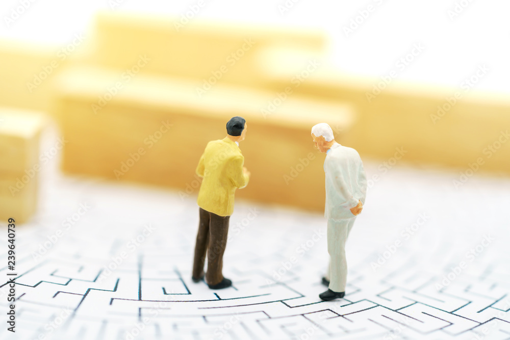 Miniature people: Businessman standing on start point of maze and thinking how to solve this problem. Concepts of finding a solution, problem solving and challenge. Miniature people: Businessman standing on start point of maze and thinking how to solve this problem. Concepts of finding a solution, problem solving and challenge.