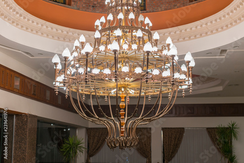 Huge chandelier in the hall. Chandelier on decoarted ceiling of a ballroom photo