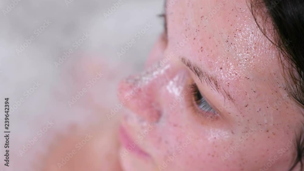 Scrub on beautiful brunette woman's face. Face close-up. Woman ia taking a bath. Scrub on beautiful brunette woman's face. Face close-up. Woman ia taking a bath.