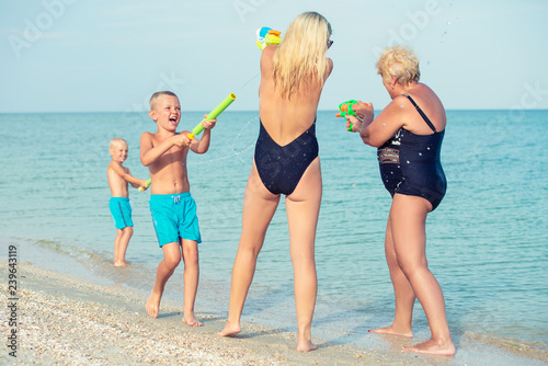 Children play with my mother and grandmother with water pistols on the beach.Summer time 