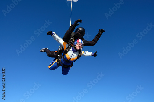 Tandem skydiving. Girl-passenger is having fun in the sky.