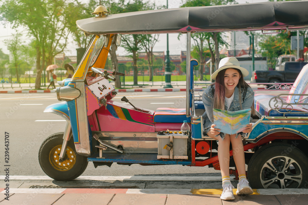  Young woman traveling people sitting on tuk tuk bangkok thailand,Cheerful woman wanderer with trendy look searching direction on location map in city centre on tuk-tuk. - obrazy, fototapety, plakaty 
