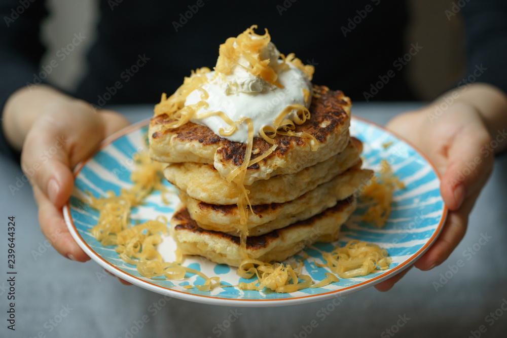 cheese pancakes topped with sourcream on fancy plate in woman hands