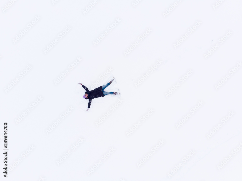 Aerial view of woman lying in snow making snow angel. Aerial view of woman lying in snow making snow angel.