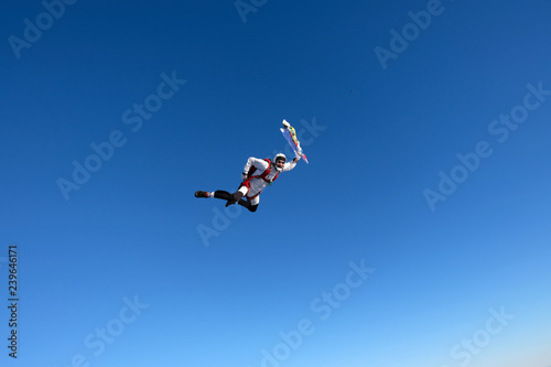Skydiver is in the blue sky.