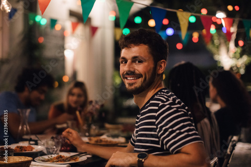 Portrait of smiling young man having dinner during party photo