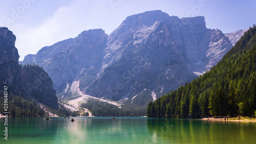 Panoramic view on emerald waters of Lago di Braies in Prags in Italian Dolomites (South Tyrol) with boats and tourists in a distance on a sunny summer day