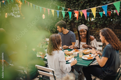 Friends having food at table during  party in backyard photo