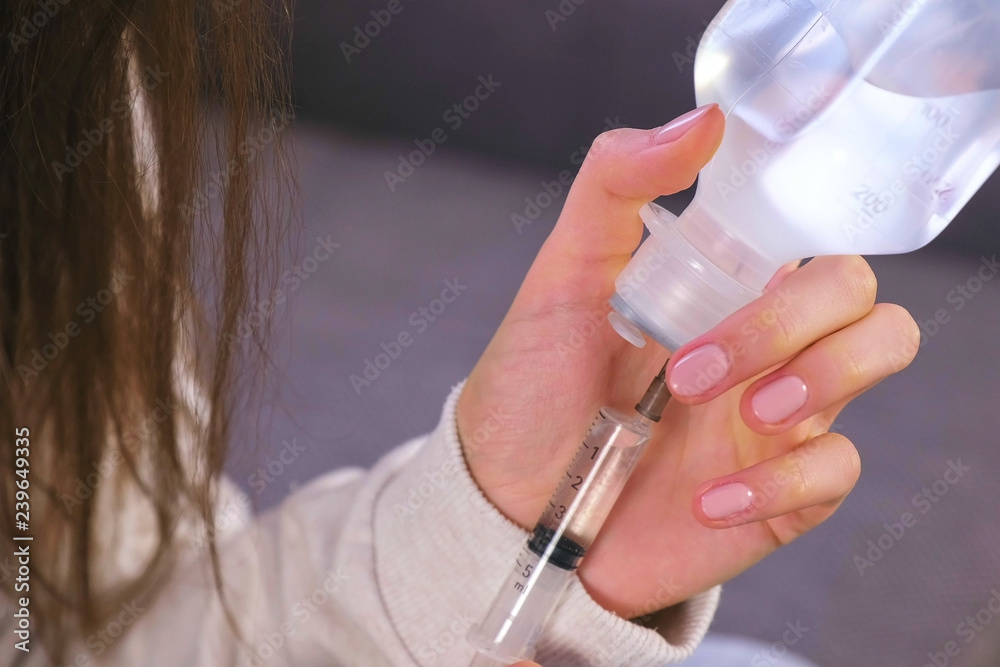 Woman picking up the syringe with saline for inhalation. Hands close-up.