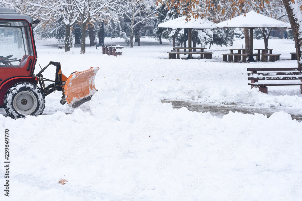 Tractor cleaning snow in the city park. Removing snow from path Tractor cleaning snow in the city park. Removing snow from path