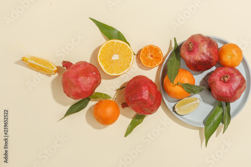 Fototapeta Naklejka Na Ścianę i Meble -  Fresh juicy tangerines, pomegranates and sliced fruits on a yellow background. Summer mood, healthy food. Top view.