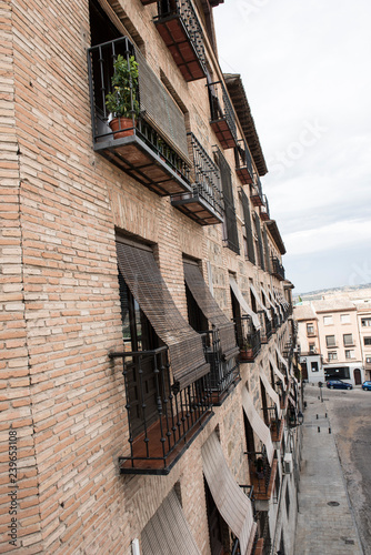 Exterior of a local building in Spain. The building seems to be a mix of old and modern architecture. The Streets seem to be narrow. It seems to be a sunny day.