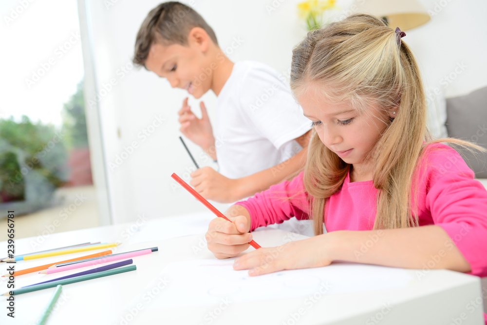 two beautiful young kids boy and girl drawing on a white paper with color pencil two beautiful young kids boy and girl drawing on a white paper with color pencil