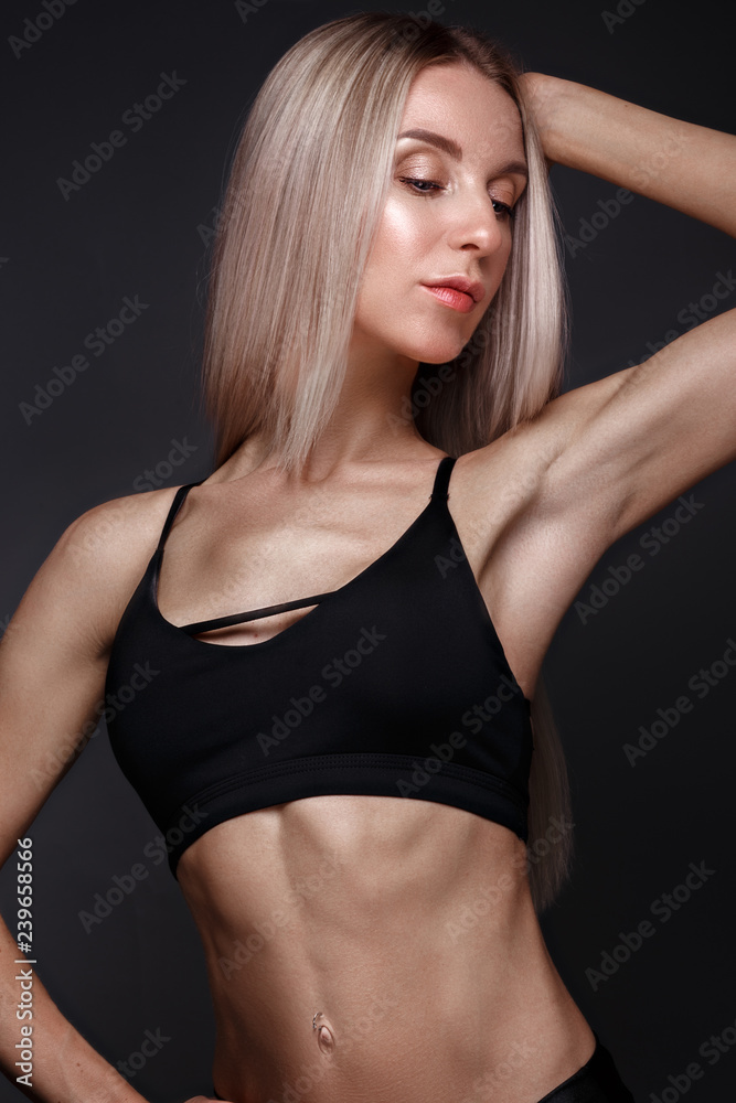 Sports girl with pumped muscles,beauty body in a tracksuit, leading a healthy lifestyle and posing in the studio.