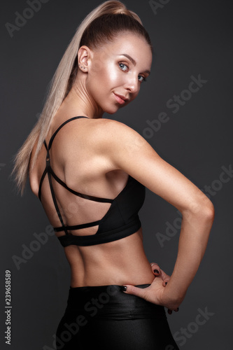 Sports girl with pumped muscles,beauty body in a tracksuit, leading a healthy lifestyle and posing in the studio.