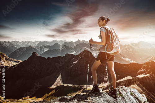Hiker with backpack and alpenstocks in mountains photo