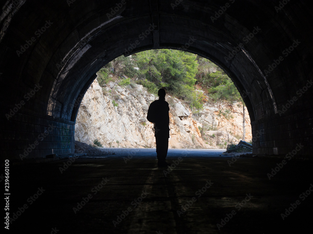 The man is standing at the entrance to the tunnel.