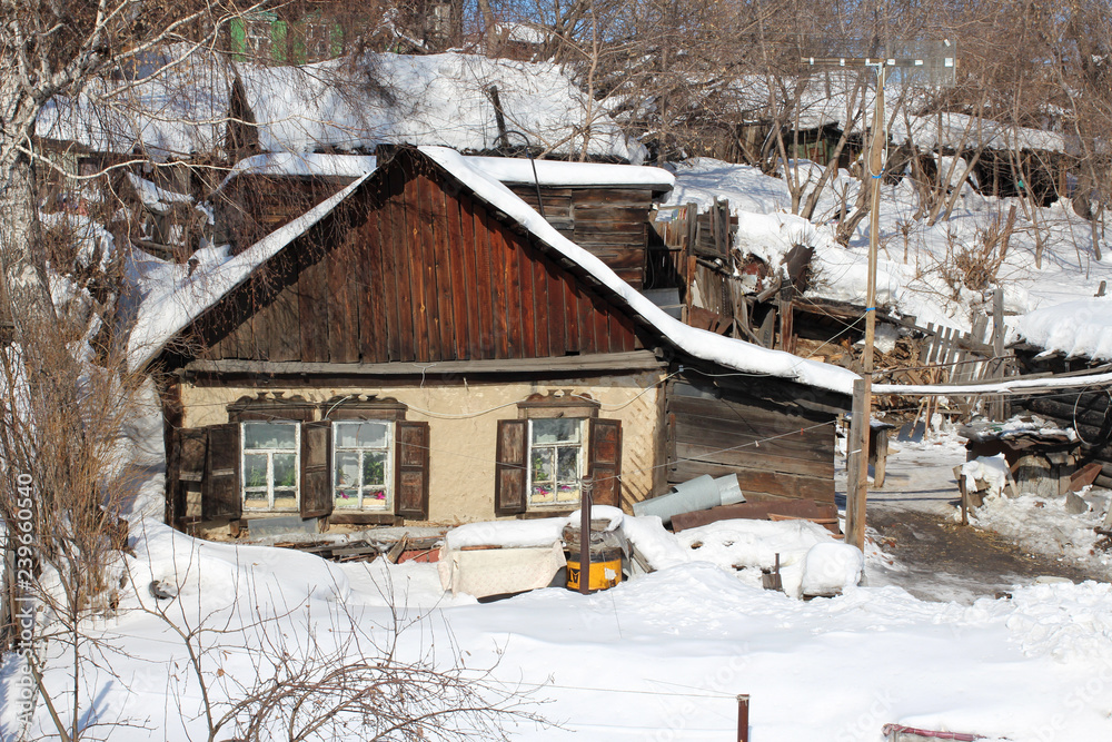 old wooden house in snow drifts in winter Siberia