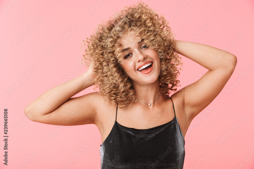 Portrait of pretty curly woman 20s wearing dress smiling while standing, isolated over pink background Portrait of pretty curly woman 20s wearing dress smiling while standing, isolated over pink background
