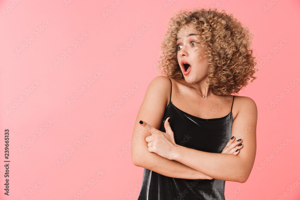 Portrait of shocked curly woman 20s wearing dress screaming while standing, isolated over pink background Portrait of shocked curly woman 20s wearing dress screaming while standing, isolated over pink background