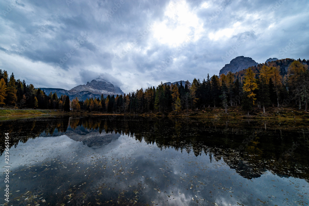 Obraz premium Autumn landscape of Antorno lake with famous Dolomites mountain peak of Tre Cime di Lavaredo in background in Dolomites, Italy. Beautiful nature scenery and scenic travel destination in Fall time.