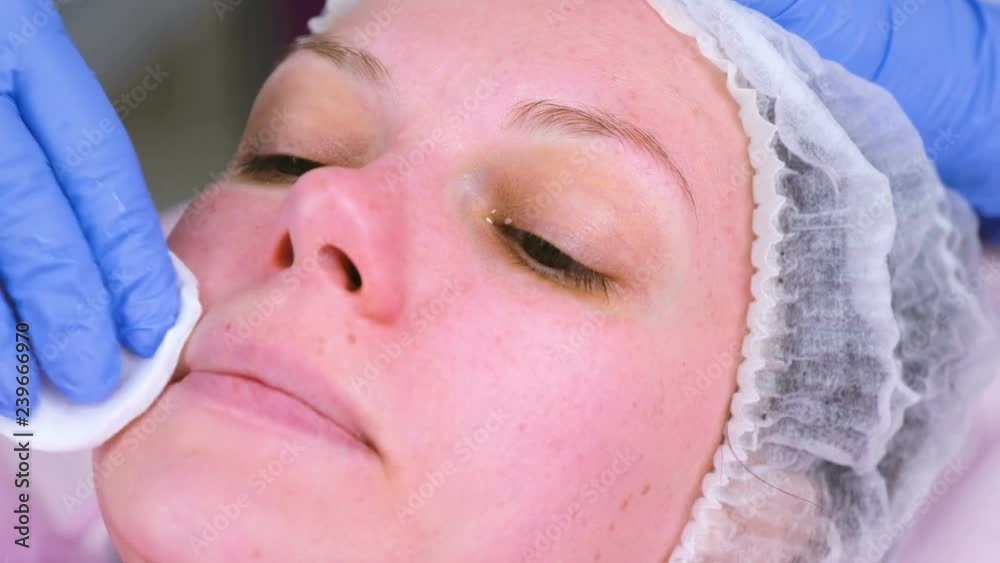 Cosmetologist washes woman's face using cotton pads. Preparing for a cleaning face. Cosmetologist washes woman's face using cotton pads. Preparing for a cleaning face.