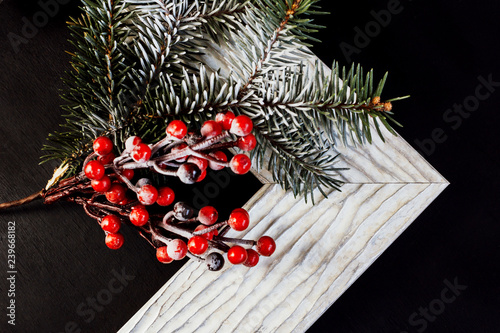 Picture frame with holly and pine branch on black background. Christmas concept.
