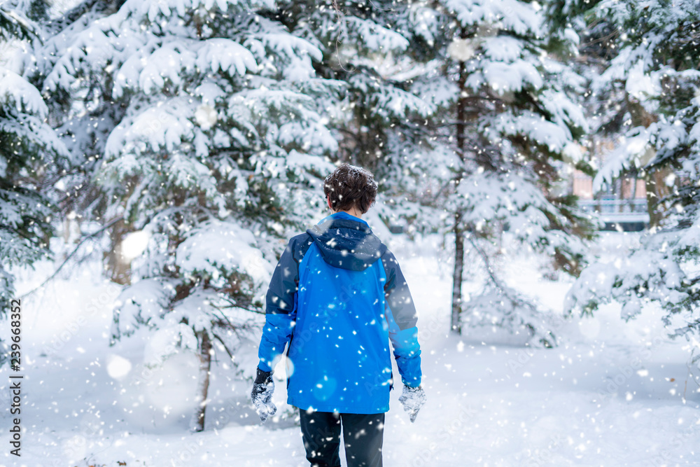 young portrait of  male teenager walking in the winter snowy forest  f