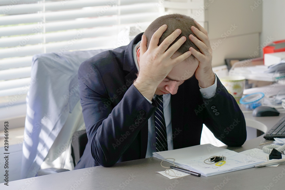 Social worker working at her desk suffering from headache migraine pain. Man hospital secretary sitting at her workplace. Health problem, stress and depression. Male holds head with hand. Social worker working at her desk suffering from headache migraine pain. Man hospital secretary sitting at her workplace. Health problem, stress and depression. Male holds head with hand.