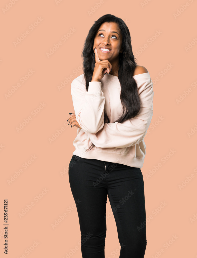 Young afro american woman thinking an idea while looking up on isolated brown background Young afro american woman thinking an idea while looking up on isolated brown background
