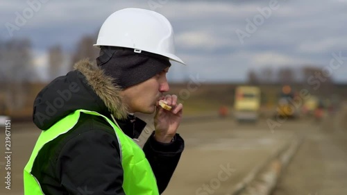 Engineer sitting on the road, eating a sandwich. Lunch break.