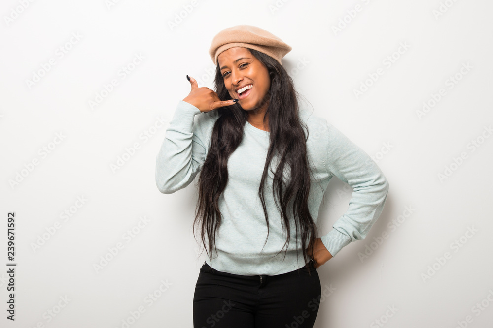 Young afro american woman on white wall making phone gesture. Call me back sign Young afro american woman on white wall making phone gesture. Call me back sign